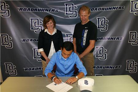 Christian Pineda signs while coaches Bruner and Meyer watch.