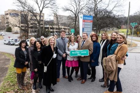 Pictured (center) are Alex and Lacy Burd, MaryEllen's son and daughter-in-law, and David Burd, MaryEllen's husband, surrounded by friends and CHI Memorial representatives for the unveiling of MaryEllen Locher Way near the CHI Memorial Hospital Chattanooga campus