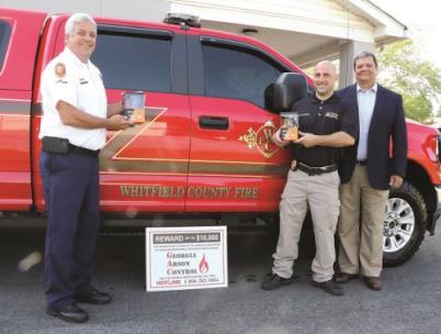 Fire Chief Ed O’Brien (left) and Investigator/Lt. Jesse Bond hold two trail cameras obtained through a grant from Georgia Arson Control, represented by consultant Ken Lecroy, who delivered the equipment Tuesday morning. The department will use the cameras to help investigate repetitive arson cases in a certain area